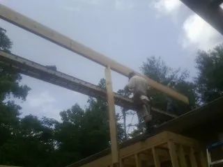 Carpenter setting a ridge beam over a new addition frame — Ice Dam Removal by Roofing Brothers in Stonyford