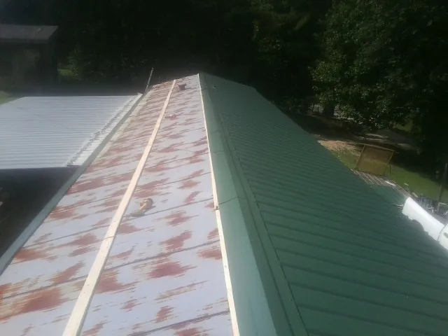 Old rusted panels beside newly installed green metal roofing — Wind Damage Roof Repair by Roofing Brothers in Stonyford
