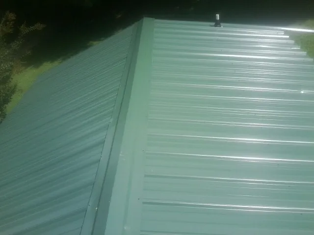 New green metal panels meeting at the ridge of a roof — Flat Roof Repair work by our crew in Stonyford