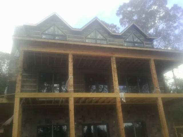 Dormers and porch framing on a large log home under construction — Roof Coating work by our crew in Stonyford