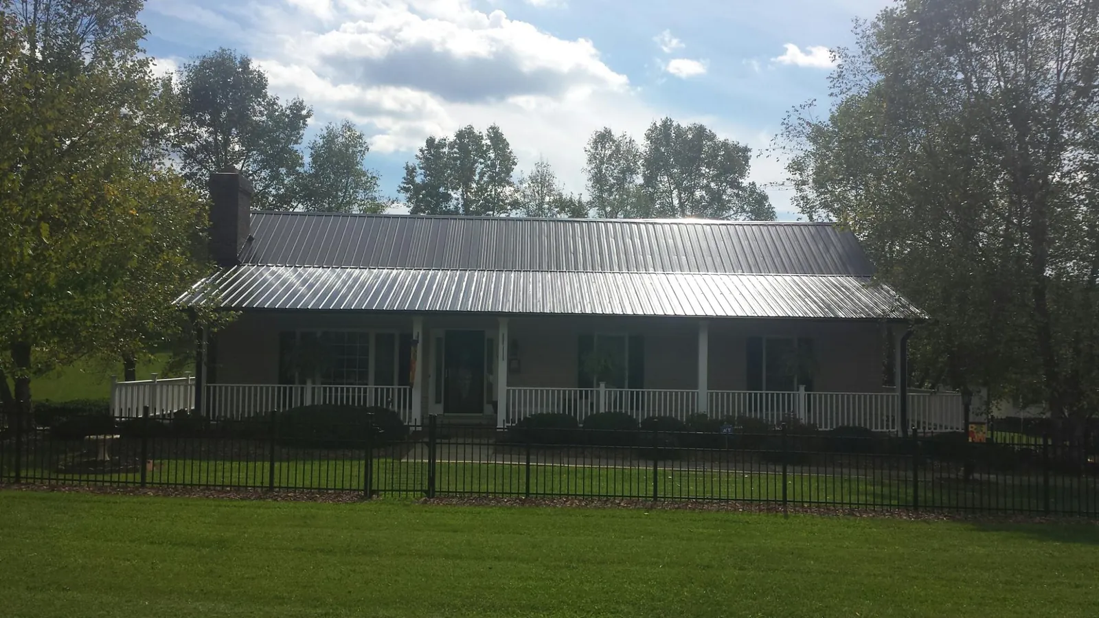 Gray metal roof on a brick ranch with a full width front porch — Gutter Guard Installation work by our crew in Stonyford