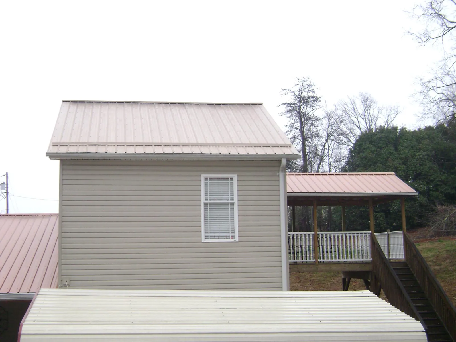 Tan metal roofs on a two story addition and attached porch, from a Roof Replacement job in Stonyford