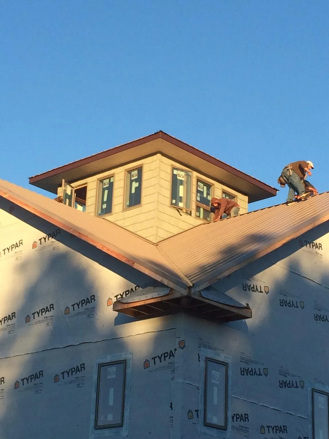 Roofers working around a rooftop cupola on a new metal roof at sunset — Roof Waterproofing in Stonyford by Roofing Brothers